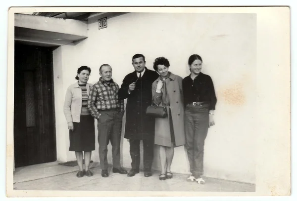 Vintage photo shows a group of people in front of house, 1970s.