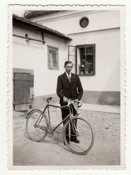 Vintage photo of a young man with bicyckle on the back yard.