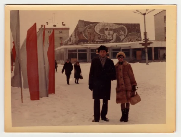 Vintage photo shows a couple poses on street in winter.