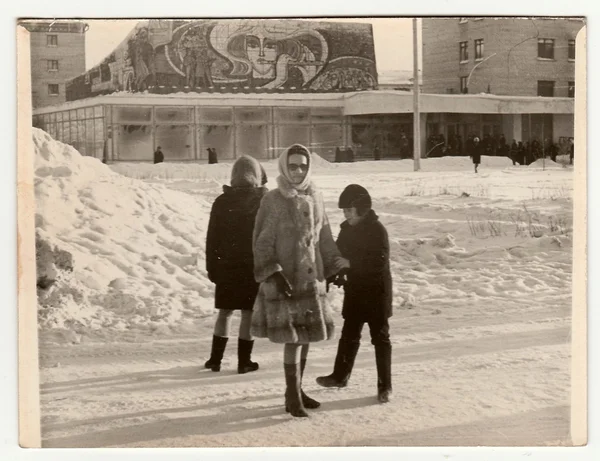 Vintage photo shows  girl poses on street in winter.