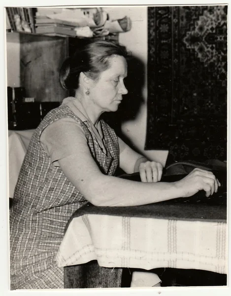 Vintage photo shows woman prepares to sew a dress.