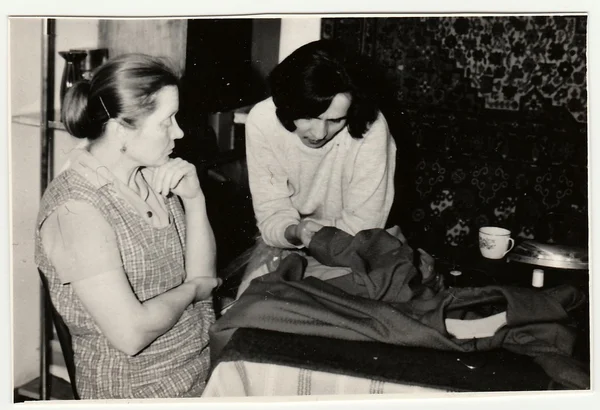 Vintage photo shows women prepare to sew a dress.