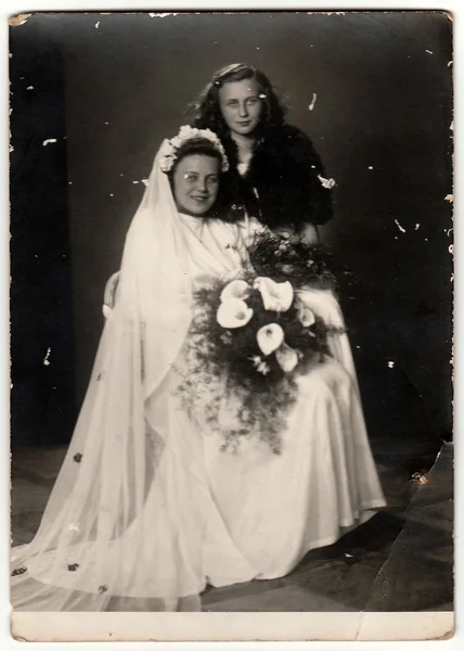 A vintage photo shows bride with her female friend.