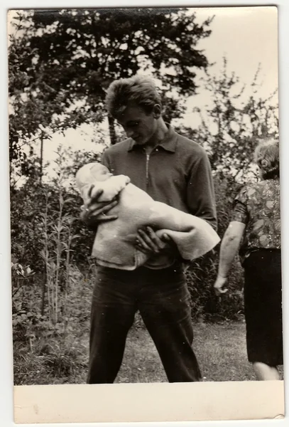 Vintage photo shows young man cradles baby.