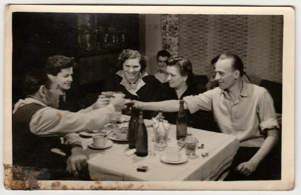 Vintage photo shows women and men propose a toast. Photo has dirt as it has been found in loft.