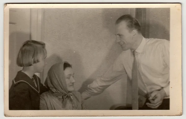 Vintage photo shows father, daughter and grandmother at home.