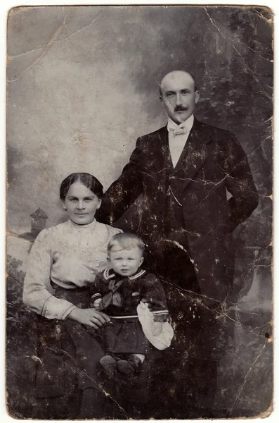 Vintage photo shows family. Small boy wears child sailor costum.