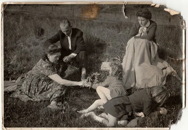 Vintage photo shows family on meadow.