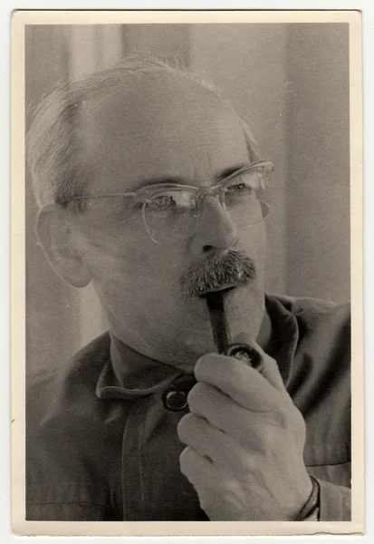 Vintage photo shows man with pipe.