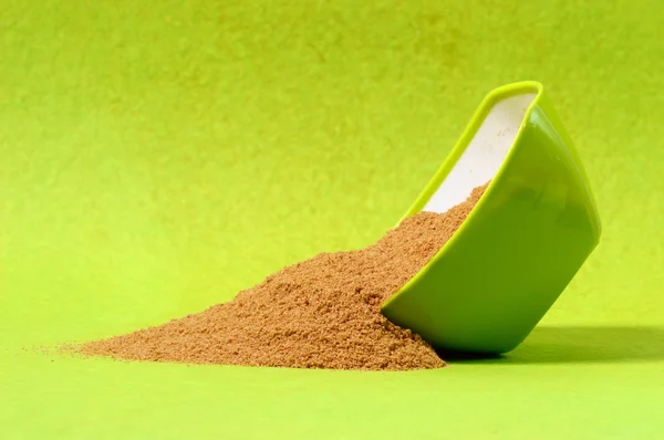 Powdered coriander in green container on green background