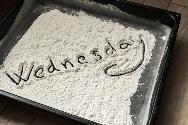 Wednesday Word Written on Baking Sheet Covered with White Flour