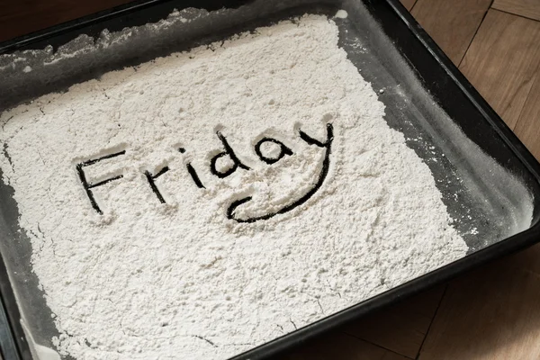 Friday Word Written on Baking Sheet Covered with White Flour