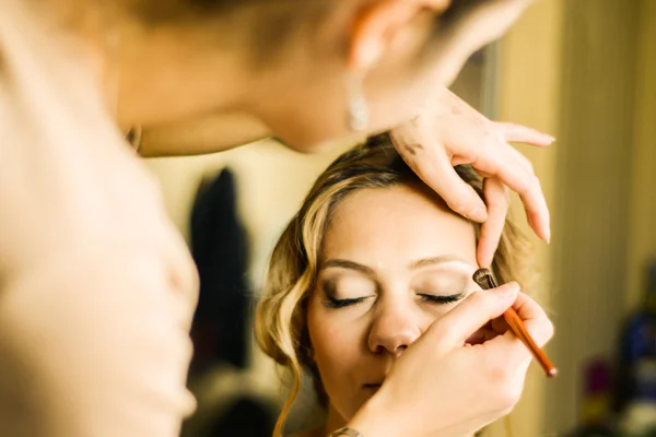 Make-up artist applying makeup on model, close up