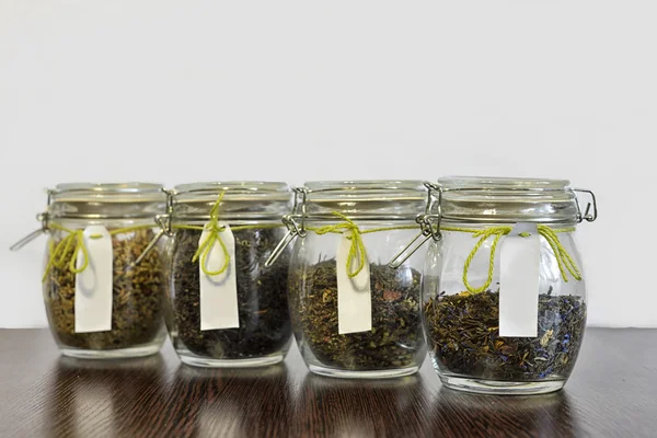 Tea in glass jars on wooden table with white background