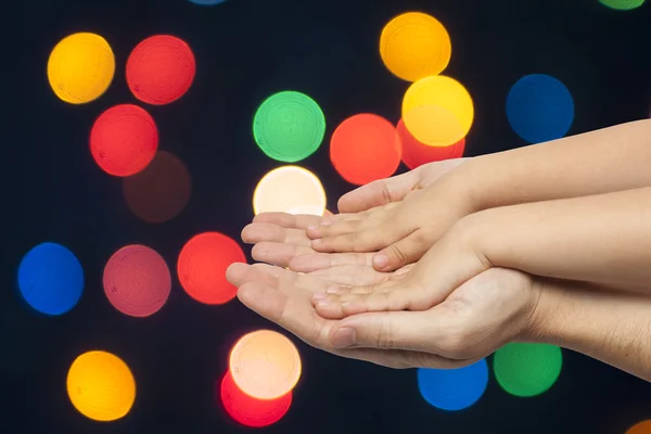 Father and son holding hands on christmas lights background.