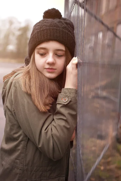 Pretty teenage girl wearing a pom pom hat in an urban setting