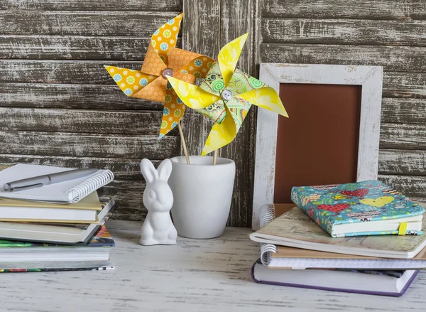 Children\'s home workspace with books, notebooks, notepads and handmade paper pinwheels and easter ceramic bunny.