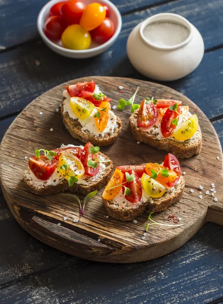 Tomato and cheese bruschetta on a rustic wooden cutting board. Healthy breakfast, snack or appetizer with wine