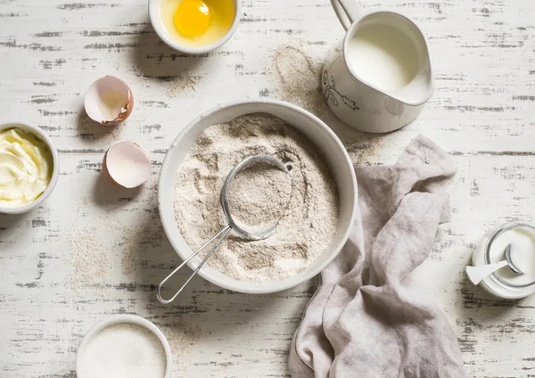 Baking rustic light background. Raw ingredients for baking - flour, eggs, milk, sugar, butter, cream. Rustic style