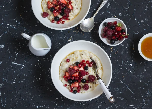 Oatmeal with berries and honey on a dark background. Healthy breakfast
