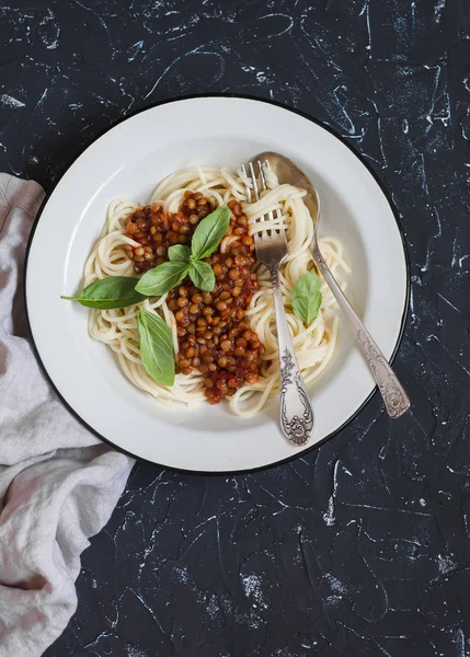 Spaghetti with vegetarian lentil bolognese on a dark background. Delicious healthy vegetarian food