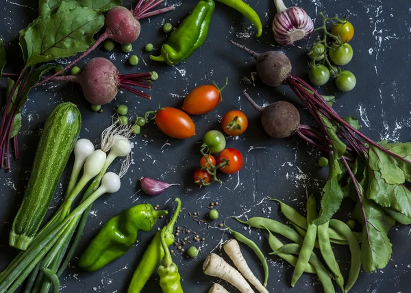 Beets, zucchini, peppers, onion, garlic, green beans, beans, tomatoes, parsnips, parsley - fresh vegetables on a dark background. Raw ingredients. Top view