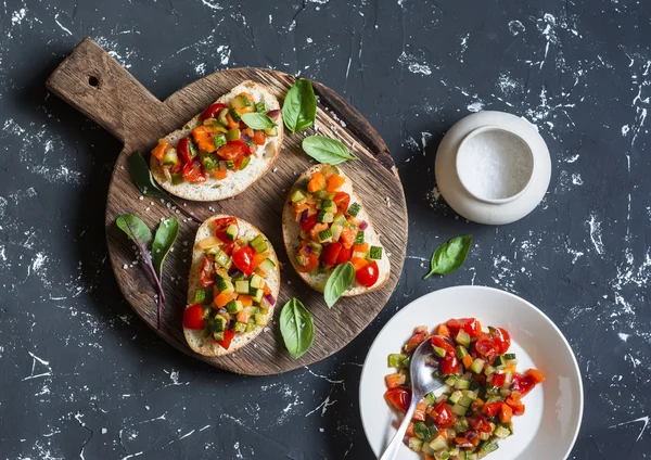 Sandwiches with quick ratatouille on rustic cutting board on a dark background. Delicious healthy vegetarian food. Top view