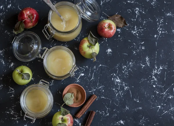 Homemade apple sauce in glass jars on dark background. Top view, free space for text. Delicious seasoning for meat