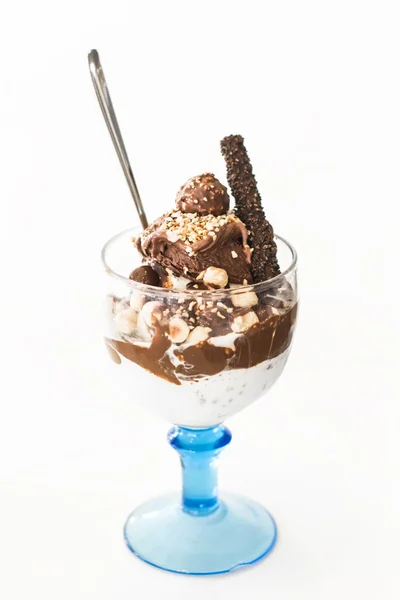 Chocolate ice cream with candy, nuts and cookies in a glass beaker