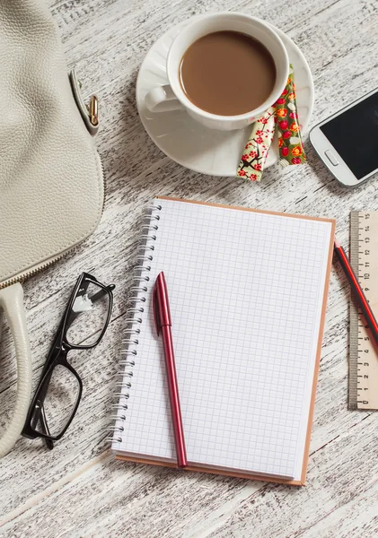 Open a blank white notebook, pen, women's bag, phone, ruler, pencil and cup of coffee