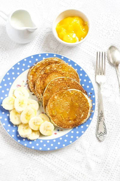 Pancake and banana slices on a blue plate on a bright surface. Delicious and healthy breakfast. Vintage and rustic style