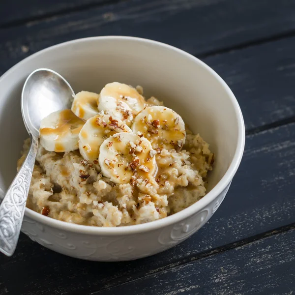 Oatmeal with caramel, banana and nuts. Healthy and delicious breakfast