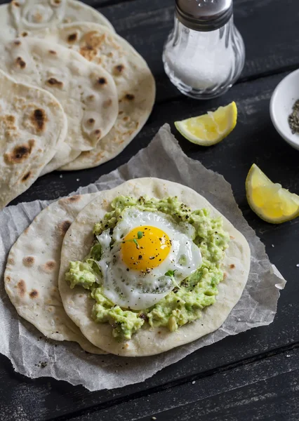 Homemade tortilla with mashed avocado and a fried quail egg. Delicious snack, healthy food