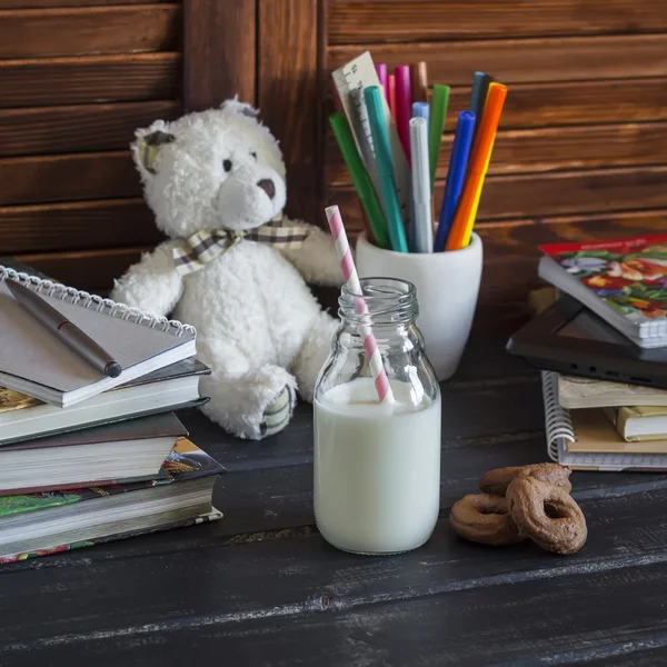 Child domestic workplace   and accessories for training and education - books, journals, notepads, notebooks, pens, pencils, tablet and toy bear, bottle of milk and biscuits.