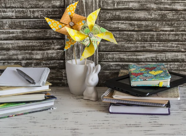 Children\'s home workspace with books, notebooks, notepads, tablet and handmade paper pinwheels and easter ceramic bunny.