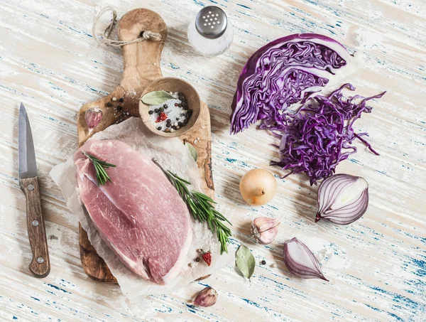 Raw ingredients - meat, red cabbage, onion, garlic, spices and herbs. Cooking delicious and healthy lunch. On light  wooden rustic background