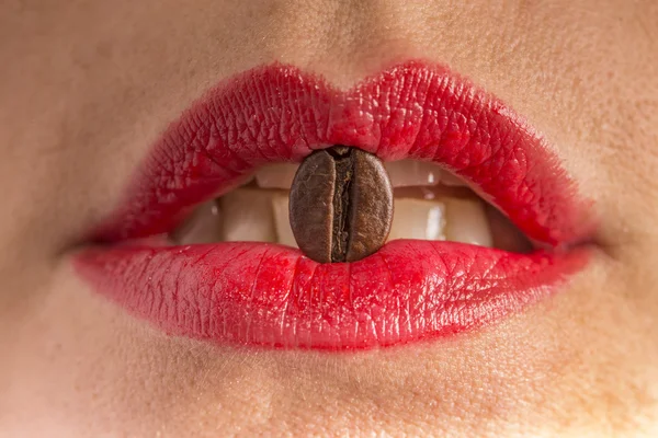 Coffee bean between red lips