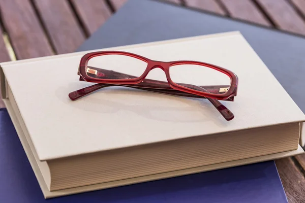 Red eyeglasses on a closed book