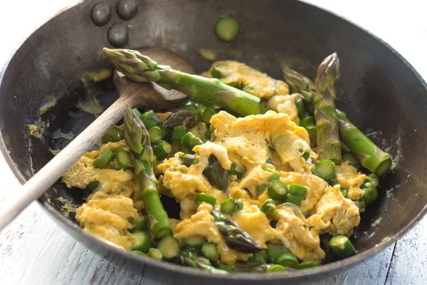 Green asparagus with egg in a frying pan.