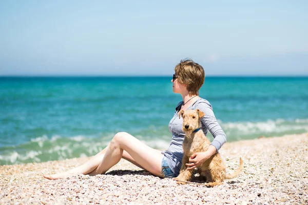 Beautiful girl  with a dog sitting on the beach