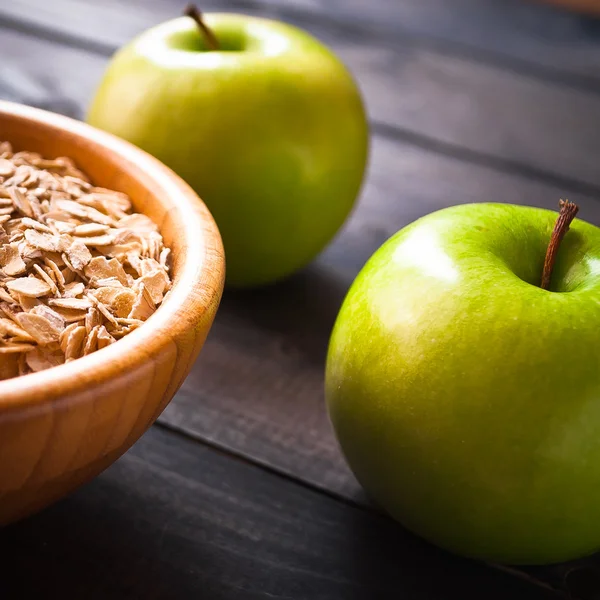 Oat flakes in bowl and two apples