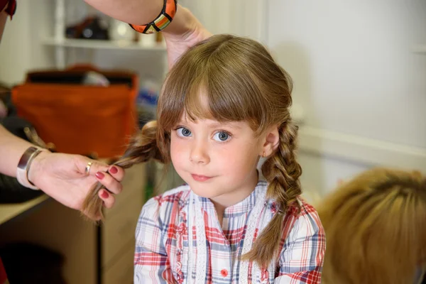 Preparation for children's photo shoot. Hairdresser makes hair girl
