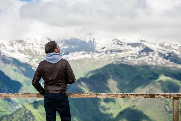 Man with hood standing at the viewpoint and looking to landscape