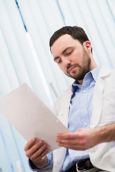 Male medicine doctor hand holding papers. Ward round, patient visit check, medical calculation and statistics concept. Physician ready to examine patient