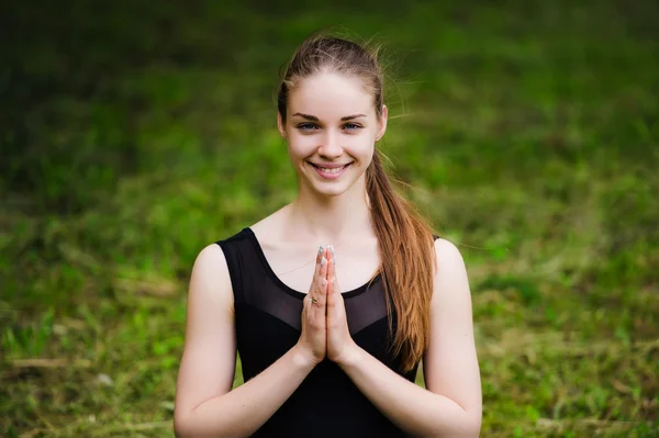 Young yoga teacher practicing outdoors in a park over green grass