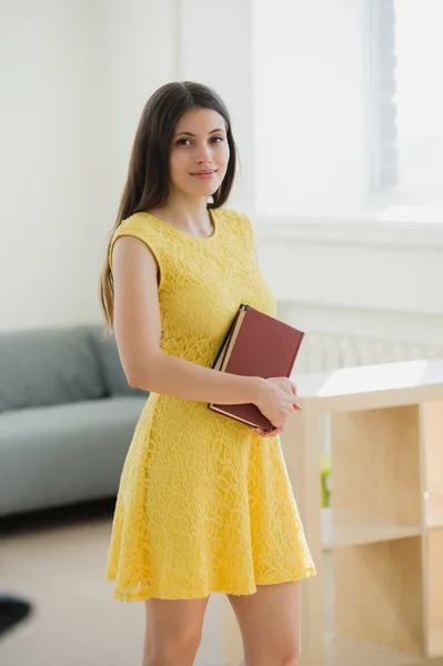 Smart beautiful Student girl wearing yellow dress holding book in school class or library