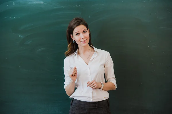 Woman pointing finger at blank board. School teacher pointing the finger at a blank board. Student stands at the blackboard. Business woman presenting the idea to the board. Girl in the school.