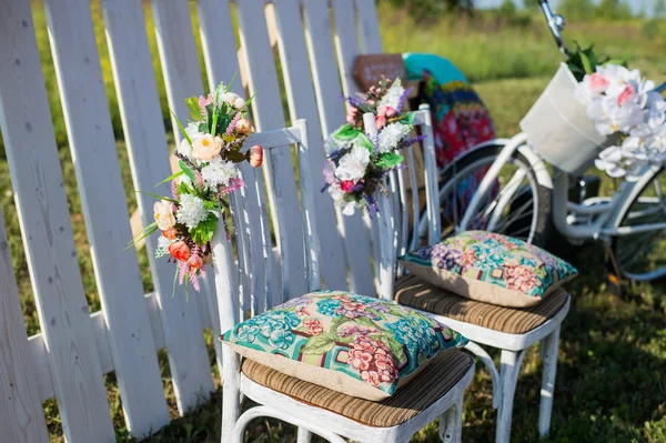 Beautiful open terrace in the garden with tiffany coloured vintage white chairs, colorful velvet pillow and fence palisade, bicycle on background decorated flowers in boho style.