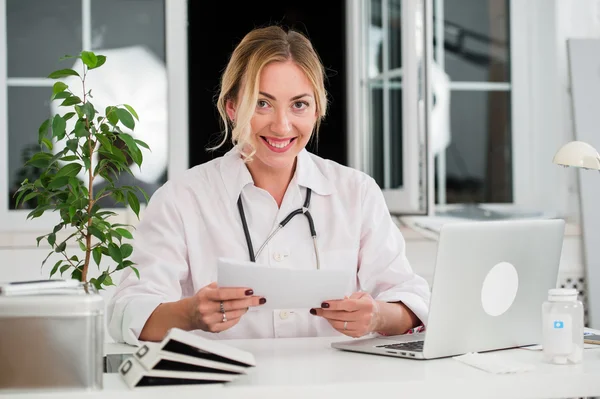 Mid adult female doctor reading documents at office desk