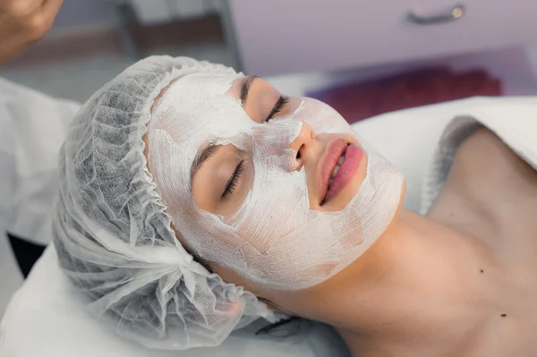 Young woman at spa procedures applying mask